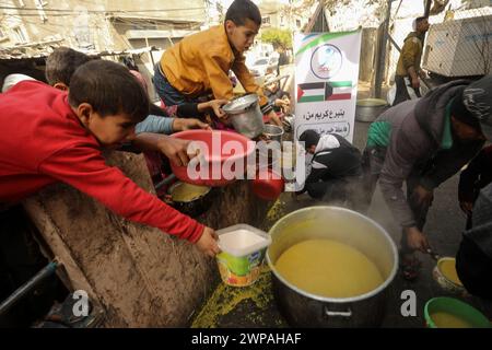 Rafah, Gaza. 06 mars 2024. Des enfants palestiniens attendent de recevoir de la nourriture préparée par une cuisine caritative dans un contexte de pénurie de vivres, à Rafah, dans le Sud de la bande de Gaza, mercredi 6 mars 2024. Les approvisionnements alimentaires, compte tenu de la poursuite du grave siège israélien, sont insuffisants dans la bande de Gaza. Photo de Ismael Mohamad/UPI crédit : UPI/Alamy Live News Banque D'Images