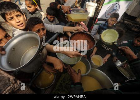 Rafah, Gaza. 06 mars 2024. Des enfants palestiniens attendent de recevoir de la nourriture préparée par une cuisine caritative dans un contexte de pénurie de vivres, à Rafah, dans le Sud de la bande de Gaza, mercredi 6 mars 2024. Les approvisionnements alimentaires, compte tenu de la poursuite du grave siège israélien, sont insuffisants dans la bande de Gaza. Photo de Ismael Mohamad/UPI crédit : UPI/Alamy Live News Banque D'Images