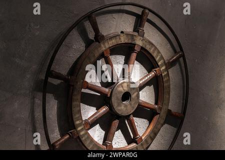 Volant en bois vintage avec des détails en laiton est sur le mur de béton gris foncé Banque D'Images