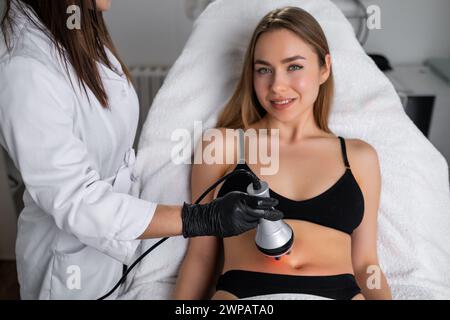 Jeune femme blonde obtenant RF lifting du corps dans un salon de beauté. Banque D'Images
