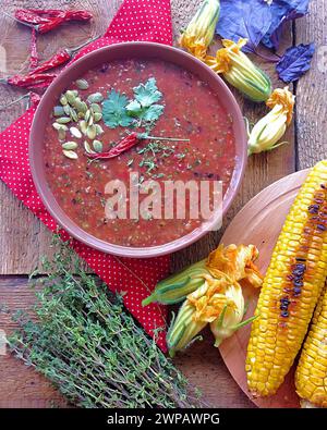 soupe de citrouille au persil vert avec du piment rouge et du maïs grillé en arrière-plan sur un fond en bois. Banque D'Images