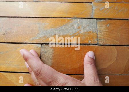 Les anciens parquets rayés doivent être entretenus. le parquet est endommagé par des rayures résultant d'une utilisation prolongée. Les mains du maître sont endommagées par le sol Banque D'Images