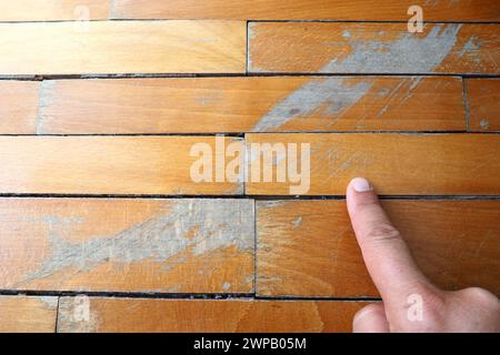 Les anciens parquets rayés doivent être entretenus. le parquet est endommagé par des rayures résultant d'une utilisation prolongée. Les mains du maître sont endommagées par le sol Banque D'Images