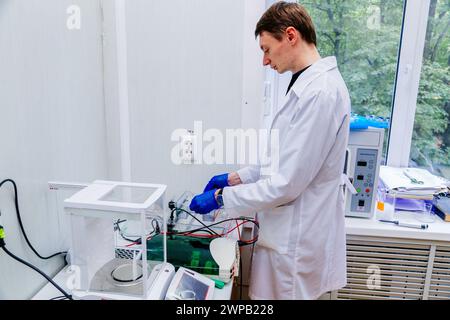 Scientifique avec la main gantée plaçant l'échantillon d'ADN dans PCR-cycler en temps réel. Banque D'Images