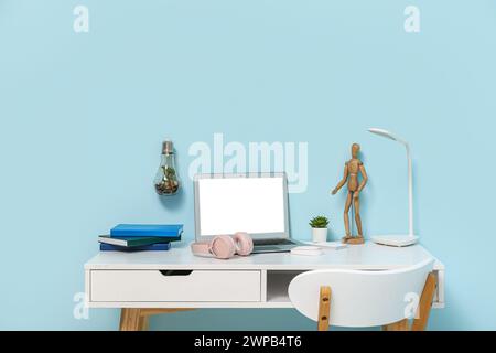 Lieu de travail élégant avec ordinateur portable, écouteurs et lampe sur table Banque D'Images