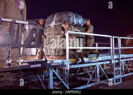 Azraq, Jordanie. 05 mars 2024. Des soldats de l'armée américaine et des aviateurs de l'armée de l'air chargent des palettes d'aide humanitaire dans la soute d'un avion C-130J Super Hercules de l'armée de l'air américaine à la base aérienne de Muwaffaq Salti, le 5 mars 2024 à Azraq, gouvernorat de Zarqa, Jordanie. L’aide alimentaire sera larguée par voie aérienne aux réfugiés palestiniens pris au piège de la guerre israélienne contre le Hamas. Crédit : SRA Lauren Jacoby/US Airforce photo/Alamy Live News Banque D'Images