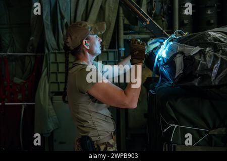 Azraq, Jordanie. 05 mars 2024. Un capitaine de chargement de l'US Air Force vérifie l'équipement de gréement sur un parachute attaché à des palettes d'aide humanitaire dans la soute d'un avion C-130J Super Hercules de l'US Air Force à la base aérienne Muwaffaq Salti, le 5 mars 2024 à Azraq, gouvernorat de Zarqa, Jordanie. L’aide alimentaire sera larguée par voie aérienne aux réfugiés palestiniens pris au piège de la guerre israélienne contre le Hamas. Crédit : SRA Lauren Jacoby/US Airforce photo/Alamy Live News Banque D'Images