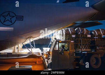 Azraq, Jordanie. 05 mars 2024. Des soldats de l'armée américaine et des aviateurs de l'armée de l'air chargent des palettes d'aide humanitaire dans la soute d'un avion C-130J Super Hercules de l'armée de l'air américaine à la base aérienne de Muwaffaq Salti, le 5 mars 2024 à Azraq, gouvernorat de Zarqa, Jordanie. L’aide alimentaire sera larguée par voie aérienne aux réfugiés palestiniens pris au piège de la guerre israélienne contre le Hamas. Crédit : SRA Lauren Jacoby/US Airforce photo/Alamy Live News Banque D'Images