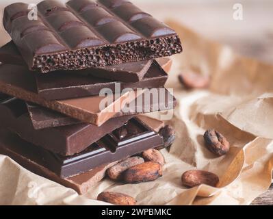 Grande pile de barres de chocolat différents types et fèves de cacao, focus sélectif. Bonne journée mondiale du chocolat Banque D'Images