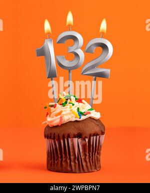 Cupcake d'anniversaire avec numéro 132 bougie - fond de couleur orange Banque D'Images