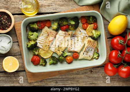 Morceaux de délicieuse morue cuite au four avec des légumes, du citron et des épices dans le plat sur la table en bois Banque D'Images