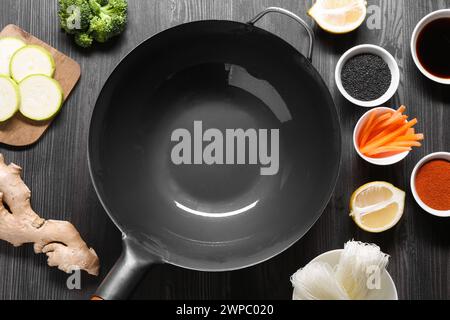 Wok en fer vide entouré d'ingrédients sur une table en bois gris foncé, plat Banque D'Images