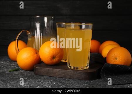 Beaucoup d'oranges mûres et de jus frais sur la table gris foncé Banque D'Images