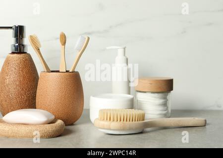 Différents accessoires de bain et produits de soins personnels sur la table grise près du mur de marbre blanc Banque D'Images