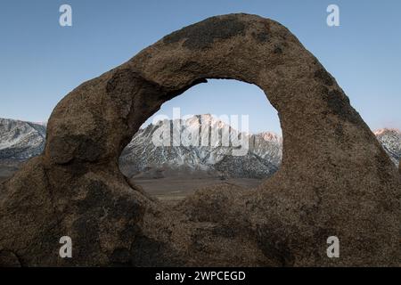 Whitney Arch, une formation rocheuse naturelle en arc, encadre le mont Whitney et la chaîne de la Sierra Nevada dans le paysage californien des Alabama Hills. Banque D'Images