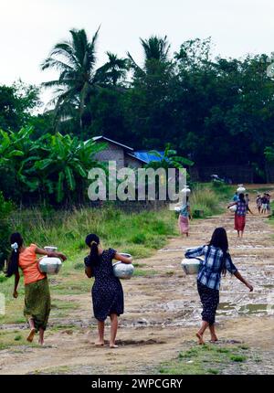 De jeunes filles arakanaises transportant des cruches à eau dans leur village de Mrauk-U dans l’État de Rakhine, au Myanmar. Banque D'Images