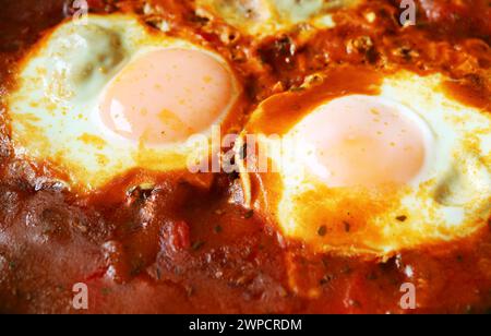 Gros plan des œufs pochés dans une sauce tomate épicée pour Shakshuka Banque D'Images