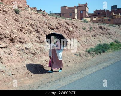 Une berbère marchant le long de la route de Quarzazate au Maroc. Banque D'Images