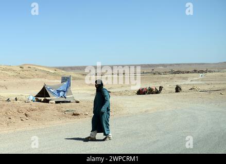 Une berbère marchant le long de la route de Quarzazate au Maroc. Banque D'Images