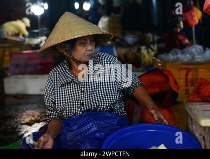 Une vietnamienne fumant un chéroot au marché aux poissons Thanh Hà à Hoi an, au Vietnam. Banque D'Images