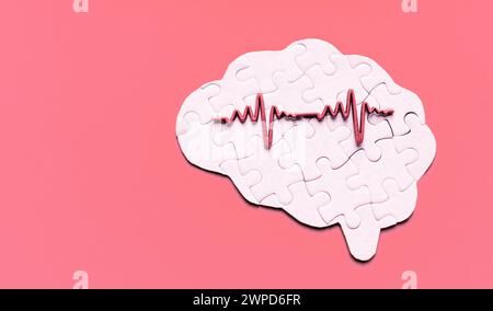 Puzzle en forme de cerveau humain recouvert d'un graphique d'électroencéphalogramme (EEG), placé sur un fond rouge troublant. Fonction cognitive et activité cérébrale Banque D'Images