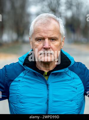 Homme senior en vêtements de sport regardant dans l'appareil photo. Symbole pour les personnes âgées qui sont actives et qui font des séances d'entraînement. Banque D'Images
