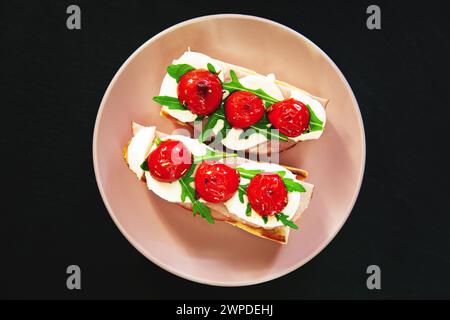 Sandwich au jambon, mozzarella, roquette et tomates cerises. Vue de dessus, fond de pierre noire. Banque D'Images