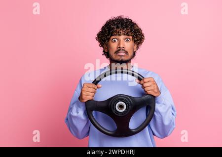Portrait photo de jeune gars gentil tenir le volant effrayé visage porter la tenue bleue à la mode isolé sur fond de couleur rose Banque D'Images