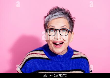 Photo du pull en tricot habillé de femme impressionné surjoyé dans des lunettes regardant à la vente incroyable isolé sur fond de couleur rose Banque D'Images