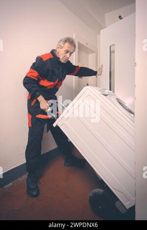 Homme plus âgé dans la machine de lavage en mouvement global sur chariot avec ascenseur Banque D'Images