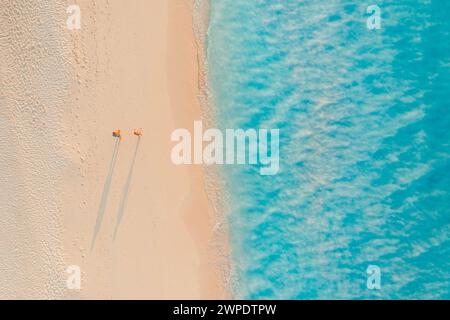 Vue aérienne romantique de couple marchant sur le coucher de soleil lumière plage longues ombres idyllique été vacances aventure humeur. Activités de loisirs en extérieur top drone Banque D'Images