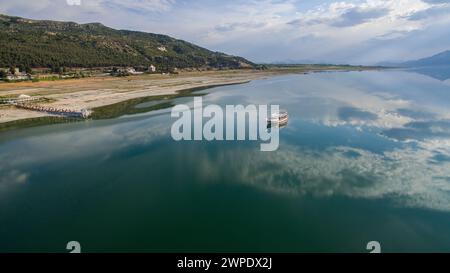 Nuages réfléchis sur le lac et un bateau voyageant sur le lac. Forêt et montagne en arrière-plan. Lac Burdur, Turquie. Banque D'Images