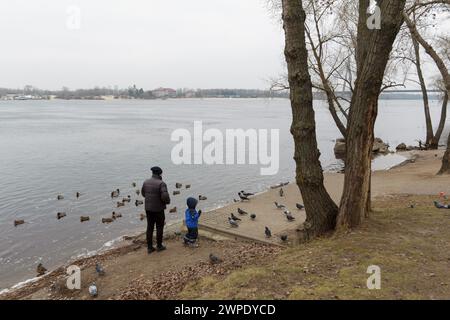 Non exclusif : KIEV, UKRAINE - 06 MARS 2024 - les gens se tiennent sur la rive de la rivière Dnipro, où le niveau de l'eau a augmenté en raison de l'augmentation de l'eau d Banque D'Images