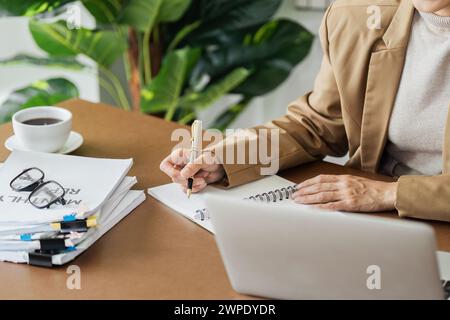 Femme d'affaires travaillant dans le plan d'écriture de bureau sur le carnet de notes et utilisez l'ordinateur portable pour planifier la stratégie de marketing. Banque D'Images