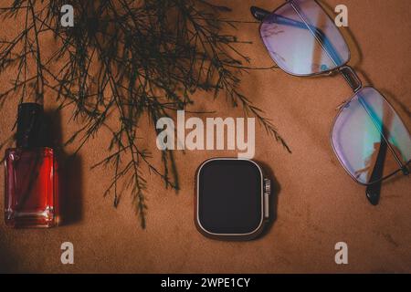 Vue de dessus de montre intelligente élégante, vernis à ongles et verre de soleil. Sur fond marron Banque D'Images