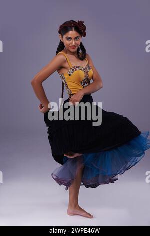 Danseuse, studio ou femme en robe dansant avec énergie, liberté ou mode en portrait pour le style. Espagnol, fond violet ou artiste en flamenco Banque D'Images