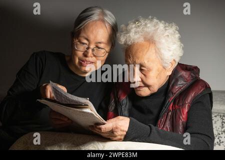 (240307) -- HARBIN, 7 mars 2024 (Xinhua) -- Jiang Shumei (à droite) vérifie une traite avec sa fille Zhang en train de souffrir chez elle dans le district de Beilin de la ville de Suihua, province du Heilongjiang, au nord-est de la Chine, le 5 mars 2024. Jiang Shumei, 87 ans, une grand-mère analphabète qui a appris à lire à l’âge de 60 ans, a peint plus de 300 peintures et publié 6 livres, réalisant une transformation étonnante dans ses années crépusculaires. Né dans le comté de Juye de la province chinoise du Shandong en 1937, Jiang vit actuellement dans la ville de Suihua de la province chinoise du Heilongjiang. En 1996, le mari de Jiang meurt dans un accident de la route. Afin de ré Banque D'Images