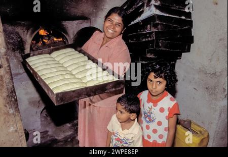 Sri Lanka, région de Minipe ; femme montre du pain à cuire dans le four derrière. Banque D'Images