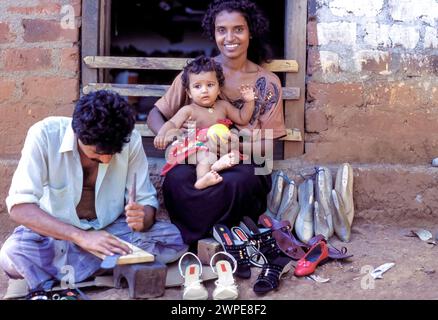 Sri Lanka, région de Minipe, cordonnier travaille à l'extérieur. Sa femme et son enfant sont assis à côté de lui. Banque D'Images
