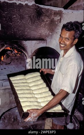 Sri Lanka, région de Minipe ; l'homme montre du pain à cuire dans le four derrière. Une petite entreprise. Banque D'Images