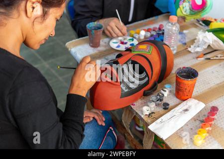 Jeune femme artisanale peignant un masque mexicain en bois de copal fait à la main, arts et artisanat dans le style alebrije, San Martin Tilcajete, vallée d'Oaxaca, Mexique. Banque D'Images