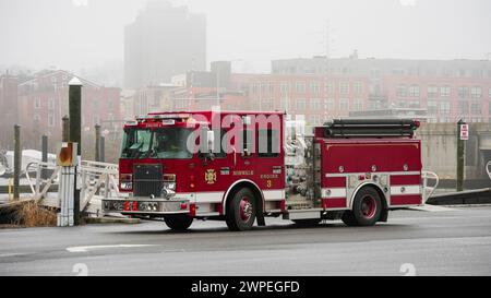 NORWALK, CT, États-Unis - 6 MARS 2024 : parking pour camions de pompiers rouges près de la rivière Norwalk près du centre-ville à Veterans Park dans le jour du brouillard Banque D'Images