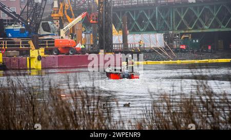 NORWALK, CT, USA - 6 MARS 2024 : Personl sont vus à bord d'un petit bateau, naviguant dans les eaux d'une rivière Norwalk dans une zone urbaine pendant const Banque D'Images