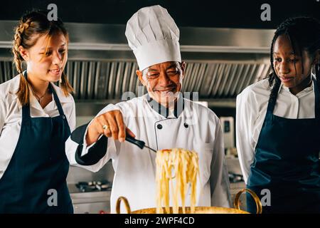 Chef guide les étudiants en cuisine. Les écolières cuisinent des nouilles japonaises. Enfants avec professeur à poêle Banque D'Images