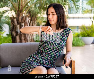 Une femme, qui est devenue fatiguée d'attendre son amie, regarde maintenant l'heure Banque D'Images