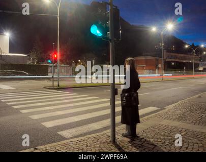 jeune femme floue debout sur le trottoir à côté d'un passage à zèbre attendant de traverser Banque D'Images