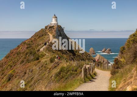 Le phare de Nugget point, de 10 mètres, au large de la route panoramique du Sud, a été allumé pour la première fois en 1870. Entouré d'îlots rocheux ou de pépites, il était automatisé Banque D'Images