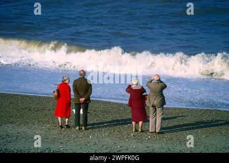 Deux couples âgés debout sur la plage donnant sur la mer en 1981, Salthouse, Norfolk Banque D'Images