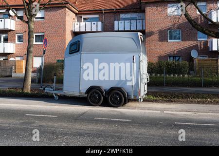Une petite remorque pour transporter un cheval debout sur le bord de la route sur le fond d'un bâtiment en briques. Banque D'Images