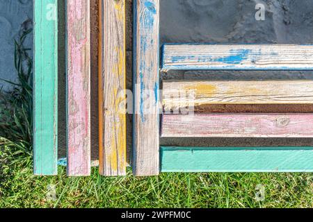 Barrière en béton avec des barres en bois colorées servant de sièges, entourant un bac à sable pour enfants près d'une pelouse luxuriante sur la journée ensoleillée vue supérieure Banque D'Images